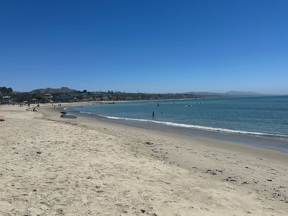 Wide sandy beach under blue sky with no clouds.