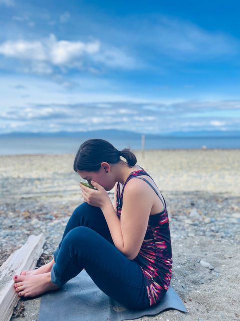 women drinking from cup sitting on the beach