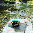 ornate cup on rock beside creek