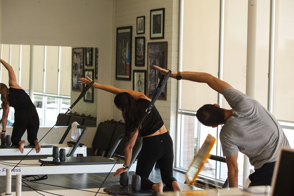 Man and woman doing a side reach movement on the Pilates Reformer