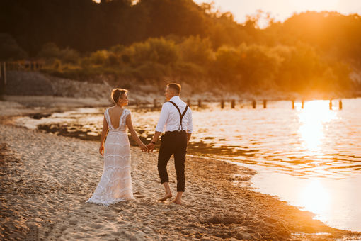 London post-wedding photo shoot, newlyweds walking along the seashore, holding hands, at sunset