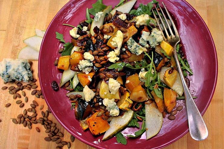 salad in a red bowl with fork and blue cheese and pumpkin seeds on a side