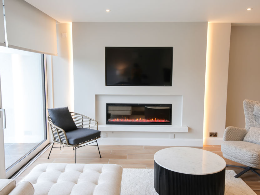 Modern living room with a fireplace and TV above, two chairs, and a coffee table