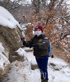 Boy in winter gear explores snowy rocks