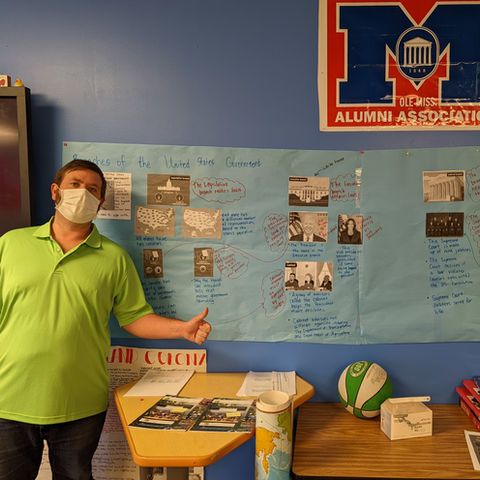 teacher in mask proudly presents his student's projects