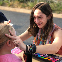 teacher paints girl's face at event