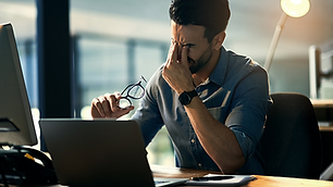 Man sitting with his head in his hands at a desk, appearing stressed.