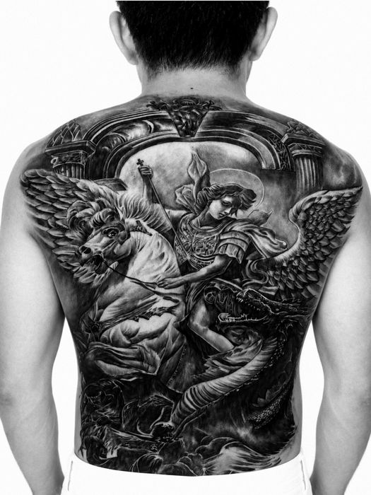 Detailed black and grey full-back tattoo of an armored archangel riding a winged horse over a dragon