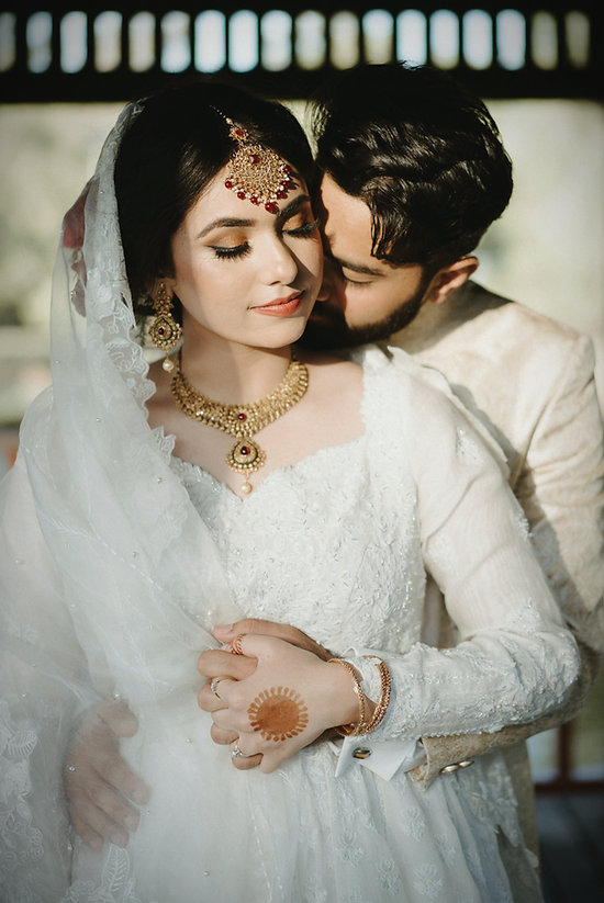 Pakistani Australian couple embracing, dressed in their traditional attire