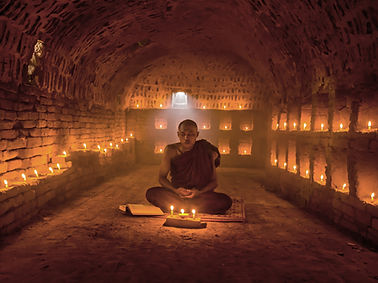 Monk Meditating with Candles