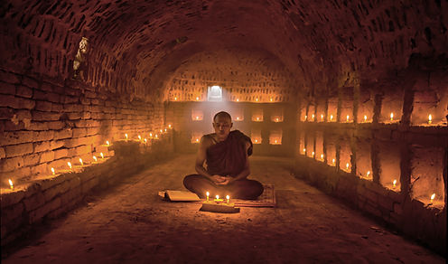 Monk Meditating with Candles