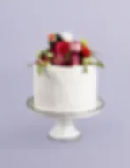 White cake on cake stand covered in peonies and roses