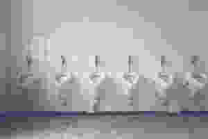 row of white urinals lined up against white tiled wall