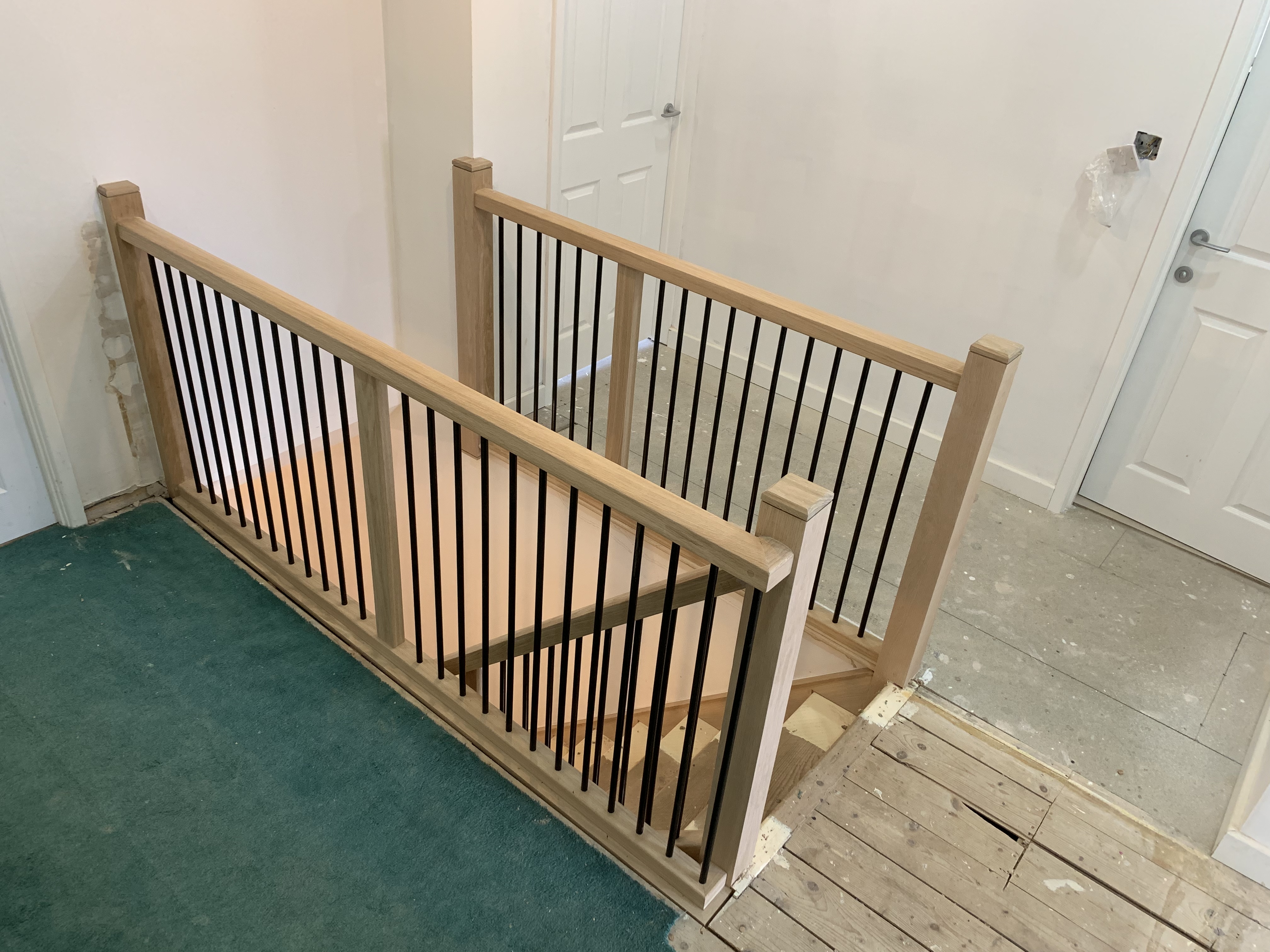 Oak cladded stair with oak handrail and black metal spindles