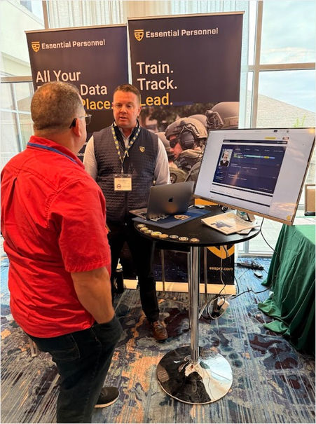 Two people talking next to the Essential Personnel sponsor table