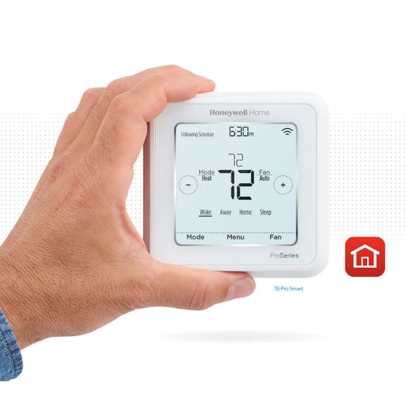 Hand holding a white digital thermostat with a home icon