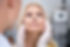 Mulher loira de meia idade tendo seu rosto avaliado por um profissional de botox com luvas descartábeis.