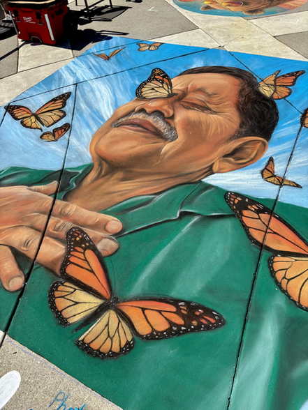 large chalk drawing on the ground of a Mexican man surrounded by monarch butterflies
