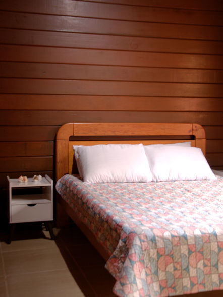 Vista da acomodação do Quarto do Casal com criado e armário conceito aberto.