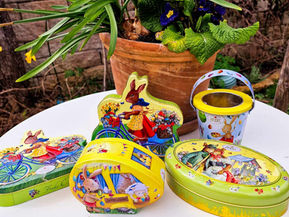 Ostersuche ohne Müll und Plastik - wiederverwendbare Verpackungen und Hacks für nachhaltige Ostern: hier auf dem Bild: Blechboxen mit Ostermotiven von gebrauchten Pralinenschachteln