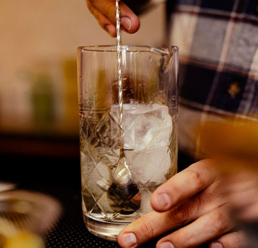 Bartender stirring a cocktail with berry garnish by Fiesta e Festa
