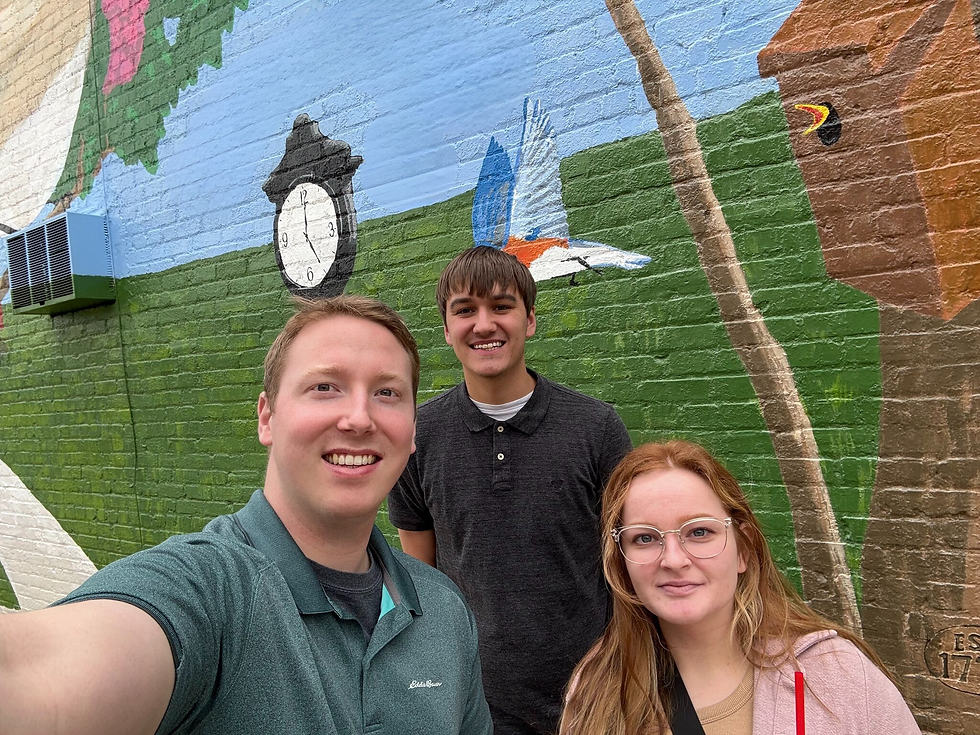 Good Stewards Shane, Blake, and Lydia in front of a community mural in a project area.