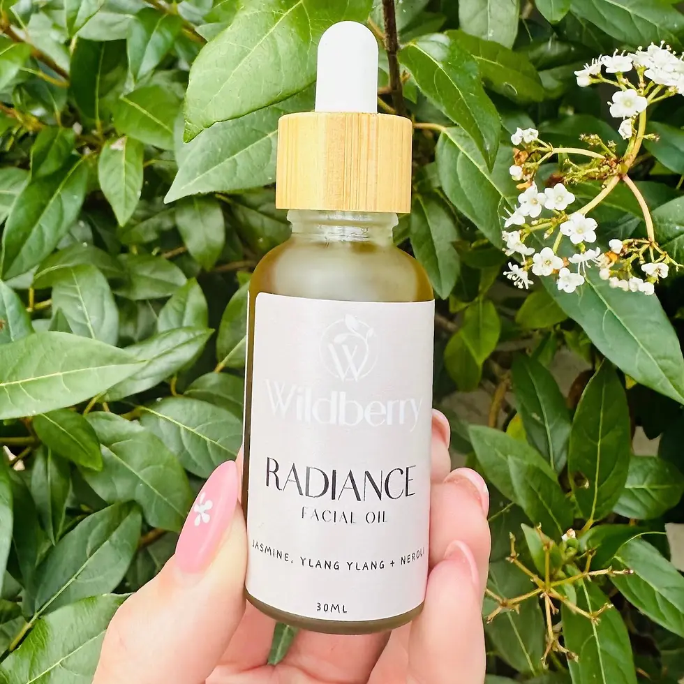 Hand holding Wildberry Radiance Facial Oil bottle with white label, green background.