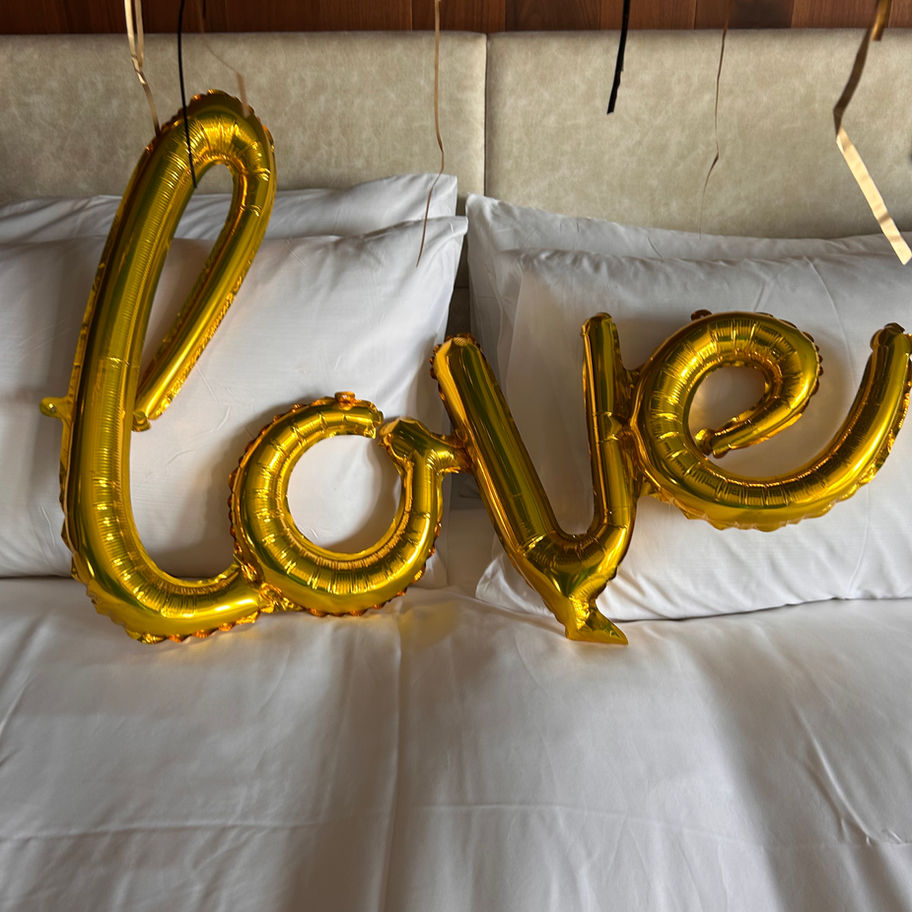 Gold foil balloon letters spelling out "love" on a bed. Valentine's Day option.