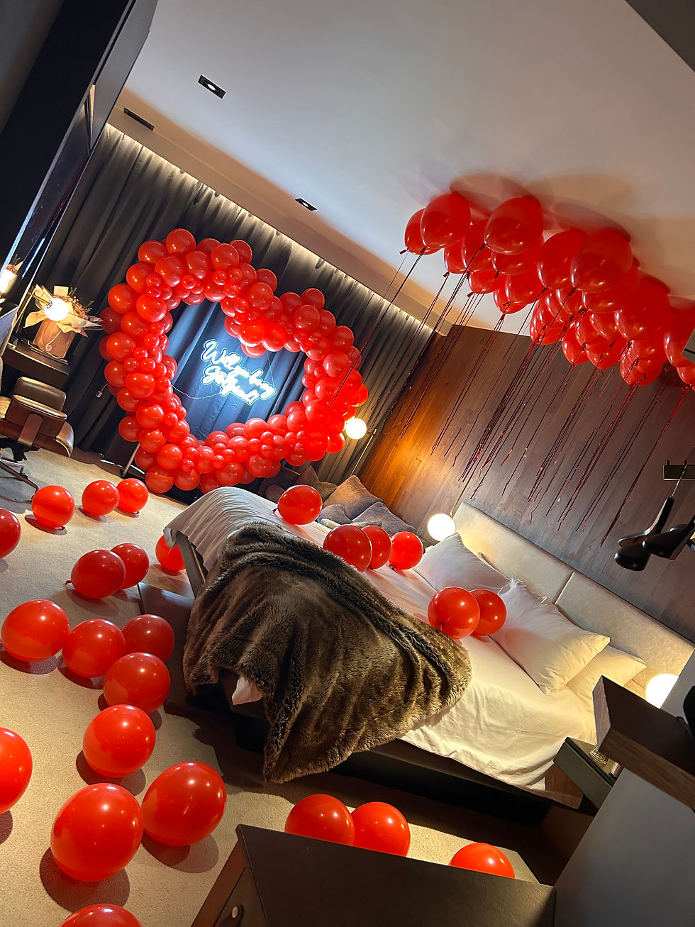 Red heart balloons, Valentine's Day decorations in a bedroom setting.