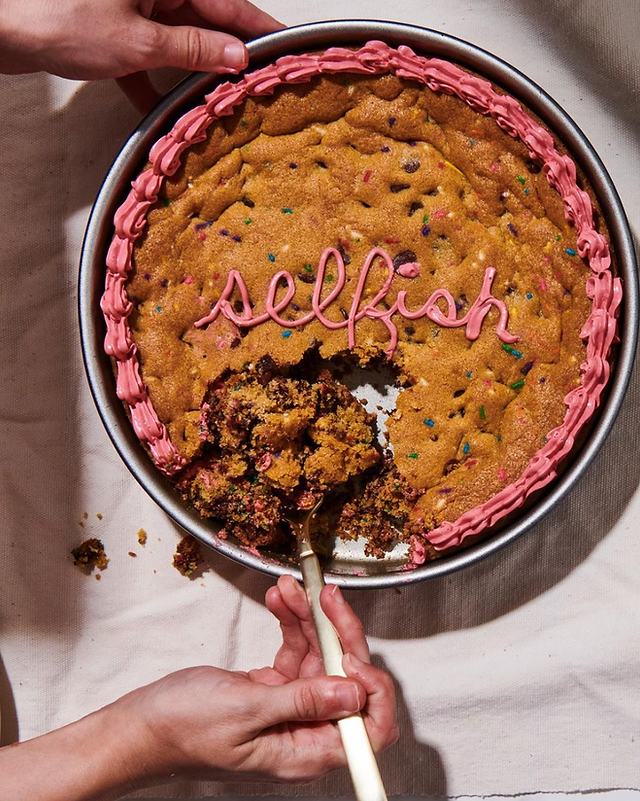 photo of a cookie cake that says "selfish" in frosting, with a forkful being taken out of it