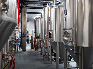 a row of stainless steel fermenters in a brewery