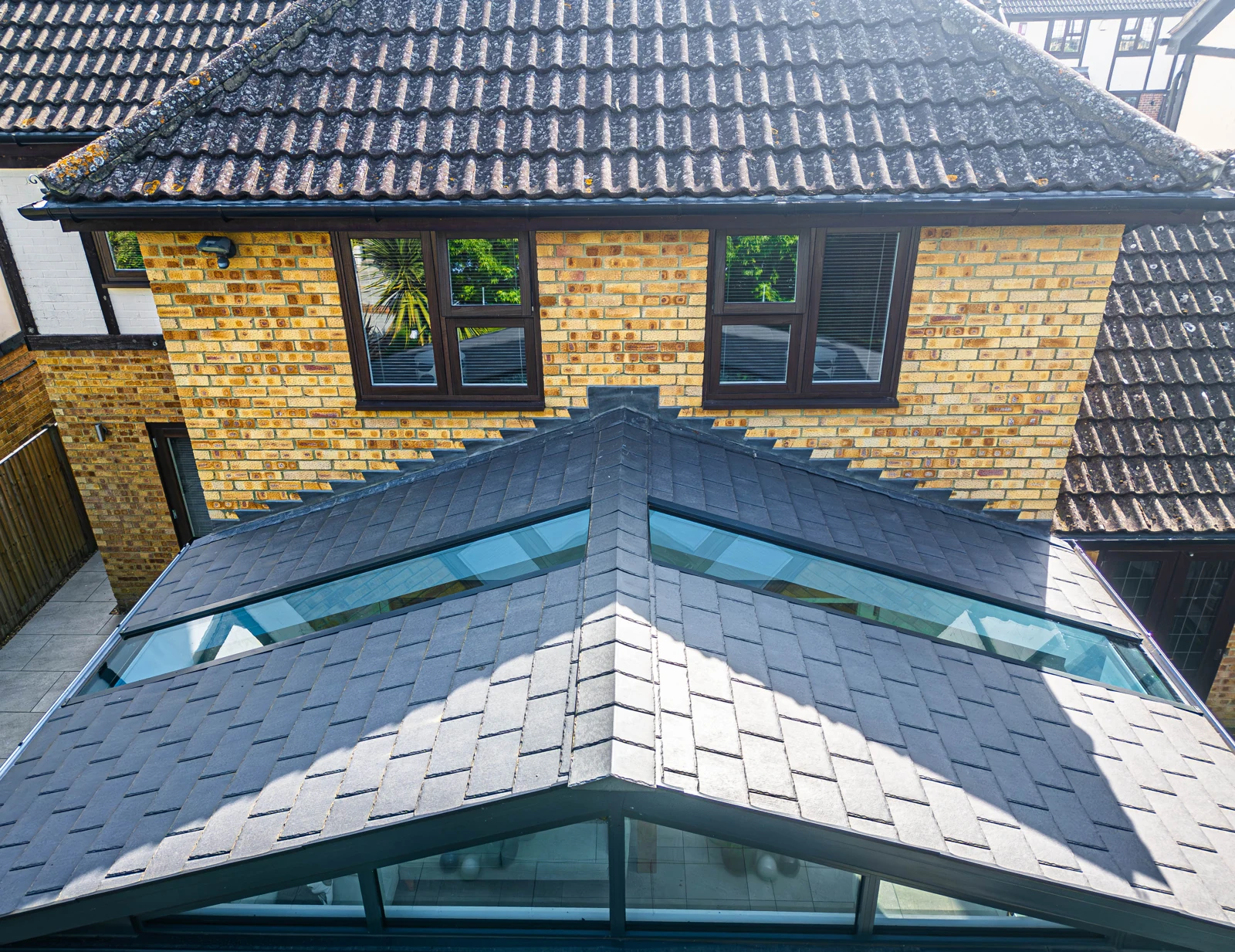 Slate-effect conservatory roof with glazed roof sections beside a brick home