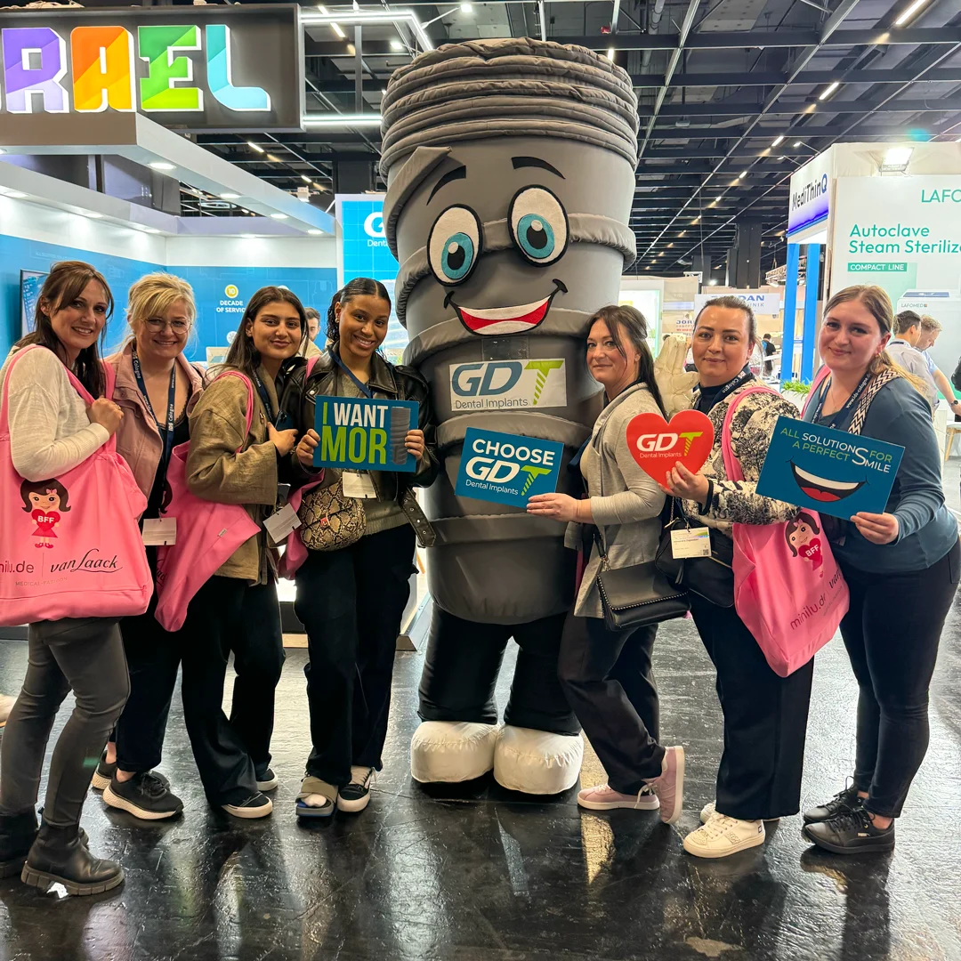 Group of women taking a picture with Smilix, The GDT mascot, at the IDS Cologne