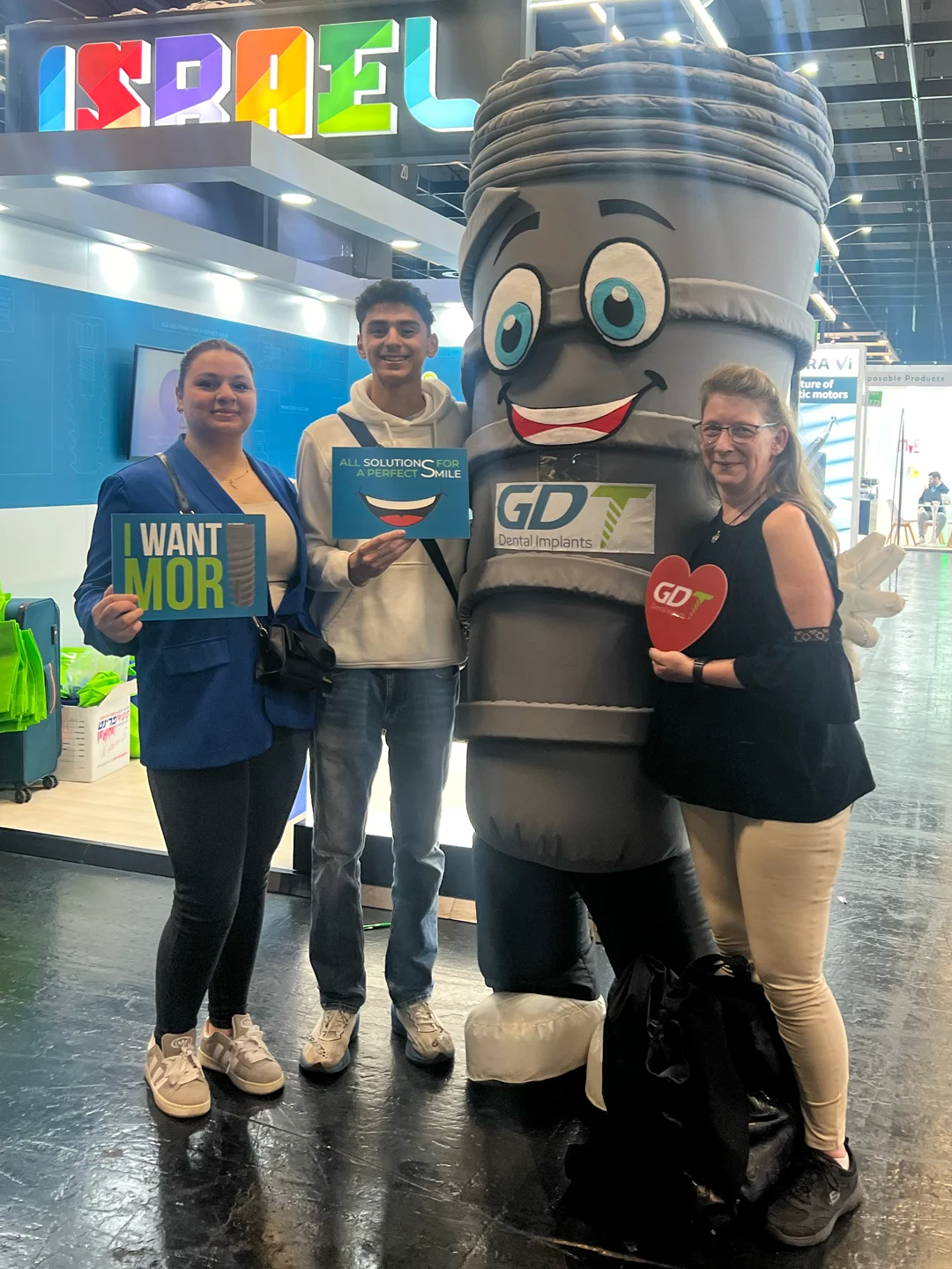 2 women and a guy posing with smilix infront of the GDT booth - IDS Cologne 2025