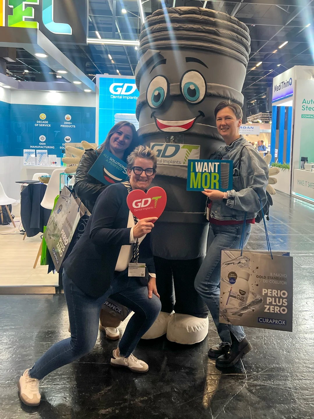 3 women posing and hugging with smilix infront of the GDT booth - IDS Cologne 2025