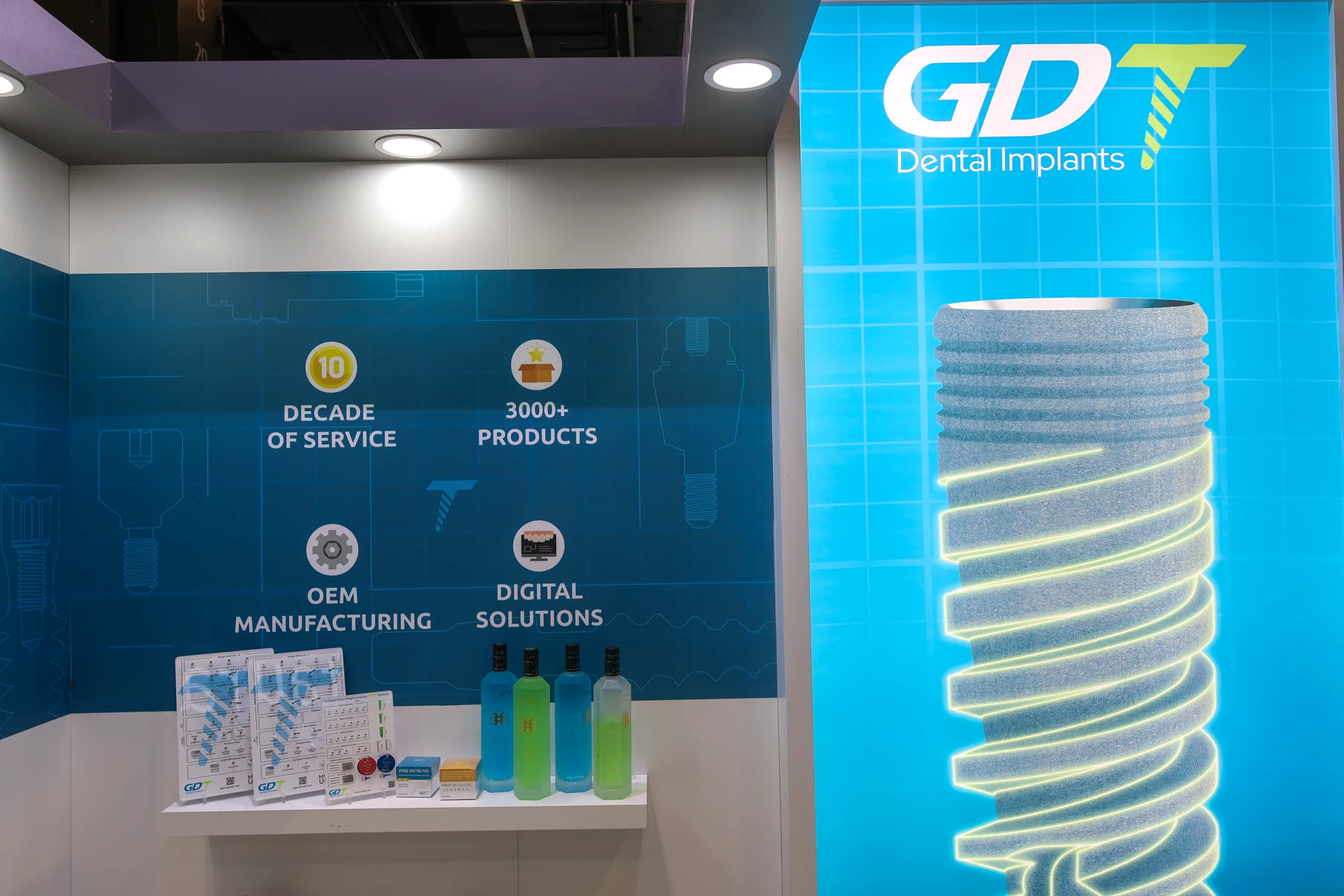 the GDT Booth main wall, glowing Implant with the GDT logo, product shelf and more - IDS Cologne 2025
