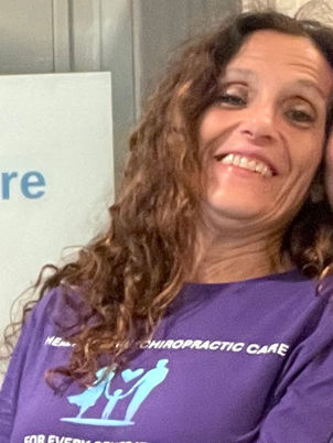 A picture of current patient with her smiling next to my front door with Healthy Family Chiropractic Care posted behind her. 