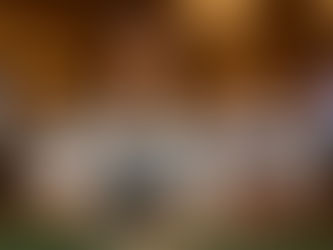 A smiling female casino dealer in a white shirt and black vest deals cards at a poker table surrounded by colorful chips under warm casino lights.