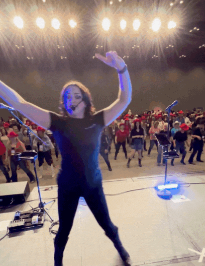 Interactive line dance lesson leading a large crowd at a Calgary corporate event. Instructor on stage teaches moves to hundreds of attendees wearing cowboy hats, demonstrating high-engagement entertainment experiences perfect for team-building, conferences, tourism groups, and Alberta holiday parties.