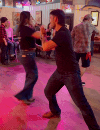 Couples social dancing modern country swing at a crowded Calgary country bar, demonstrating real-world partner dance connection, floorcraft, and community-driven western social dancing.