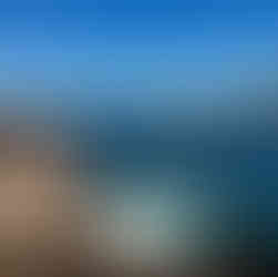 People swimming in the ocean in Madeira Portugal while others dive off of a diving board at Porto Moniz