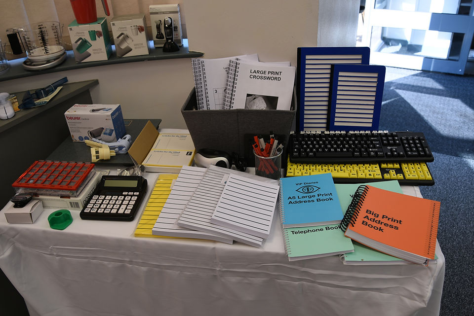 A display of the various accessible stationary items, including large print books, writing guides, large labelled keyboards and calculators.