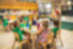 Gan Sinai preschool students raising their hands during a classroom learning activity.