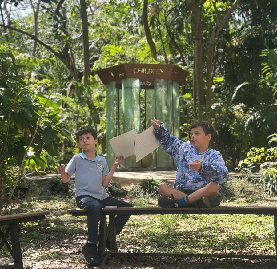 Children sitting together outside under trees at Temple Sinai youth programs in Miami.