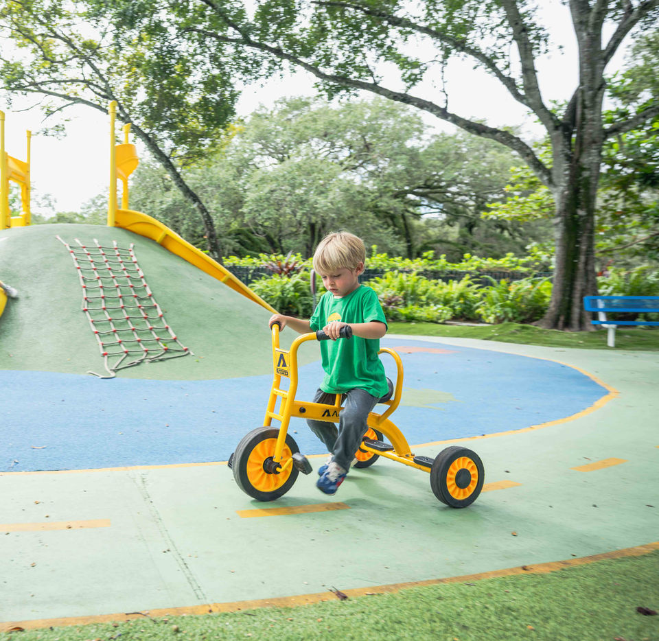 Young child riding a tricycle on the Gan Sinai playground.