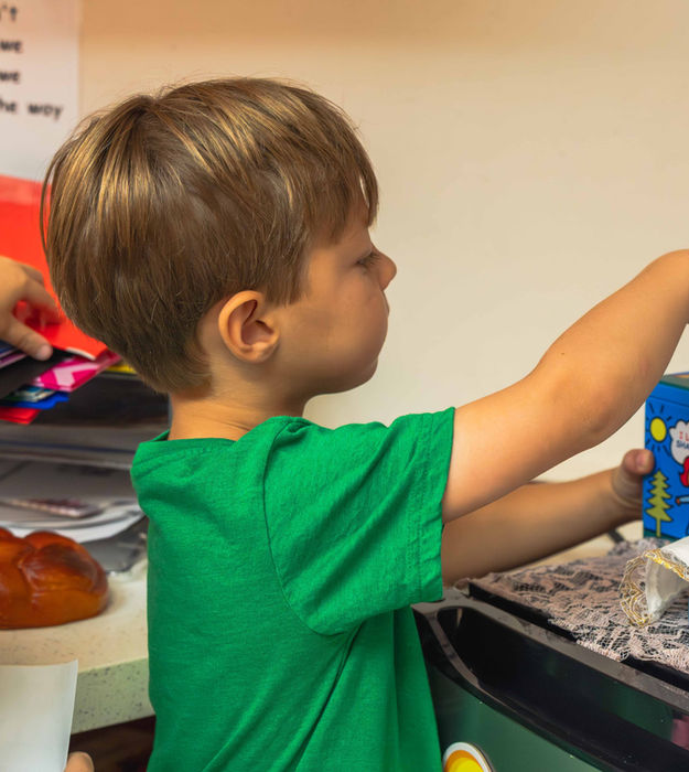 A young learner puts money in a tzedakah box
