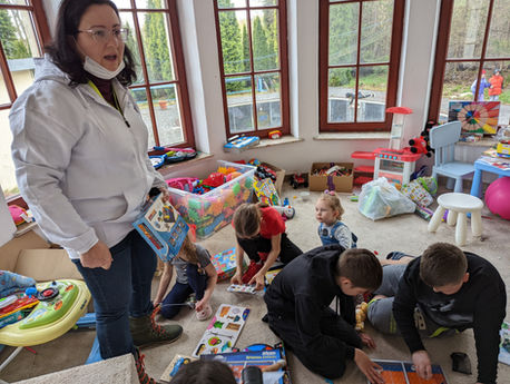 A woman standing over children playing in a children room.