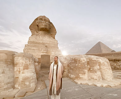 a woman stands in front of the sphinx at the full moon