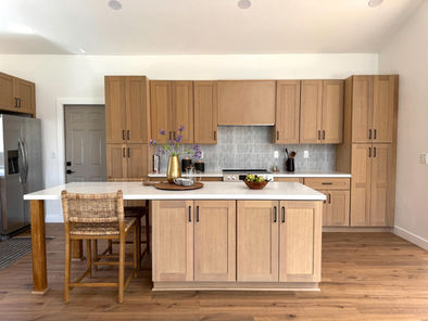Light wood kitchen cabinets with white island in open-concept space