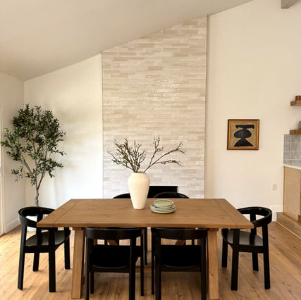Dining space with wood floors, black chairs, and textured tile chimney reaching up to the ceiling